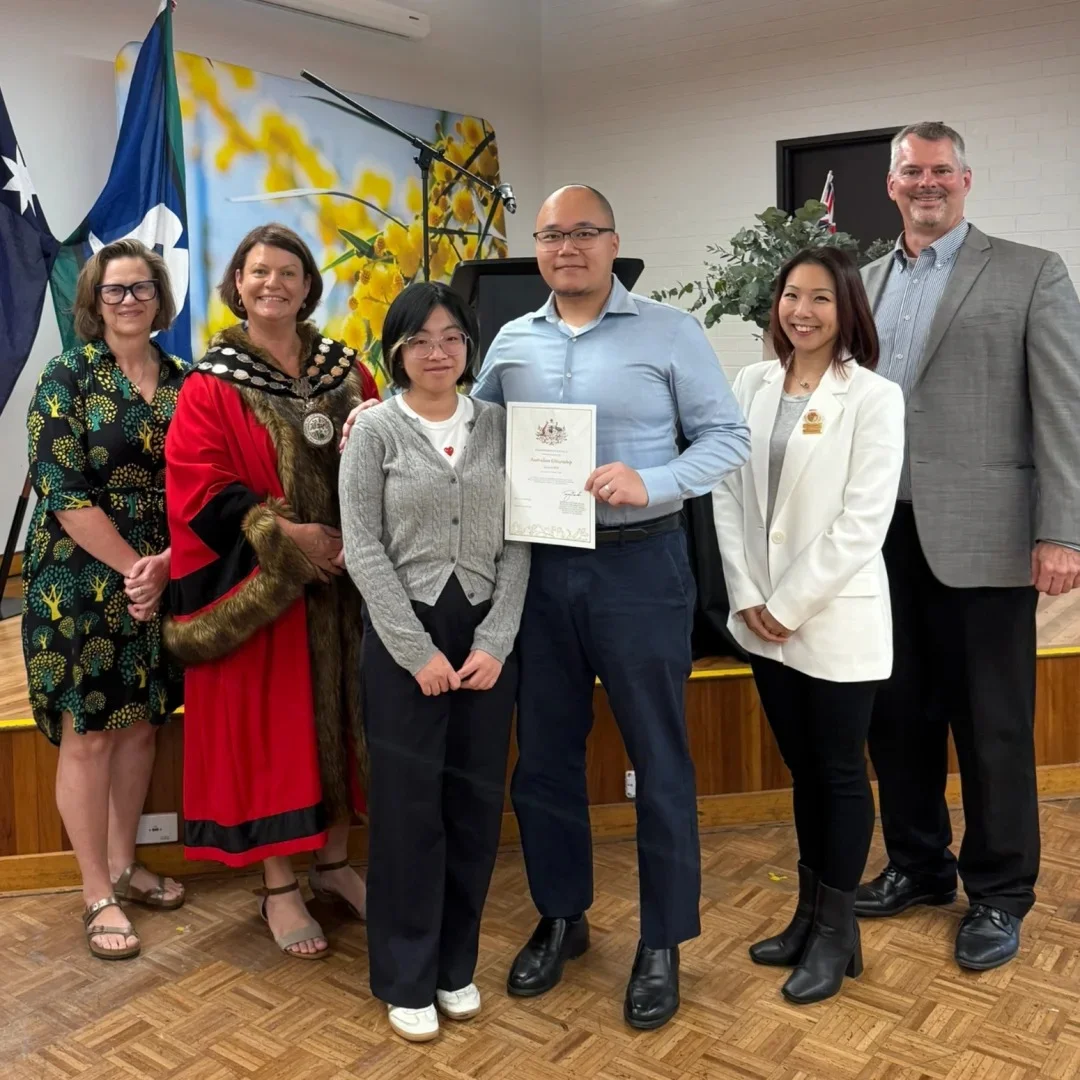 Family at Australian citizenship ceremony with official — mother, father, child holding Australian flags