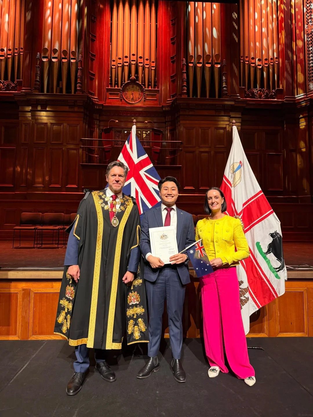 New citizen receiving citizenship certificate from Mayor on stage