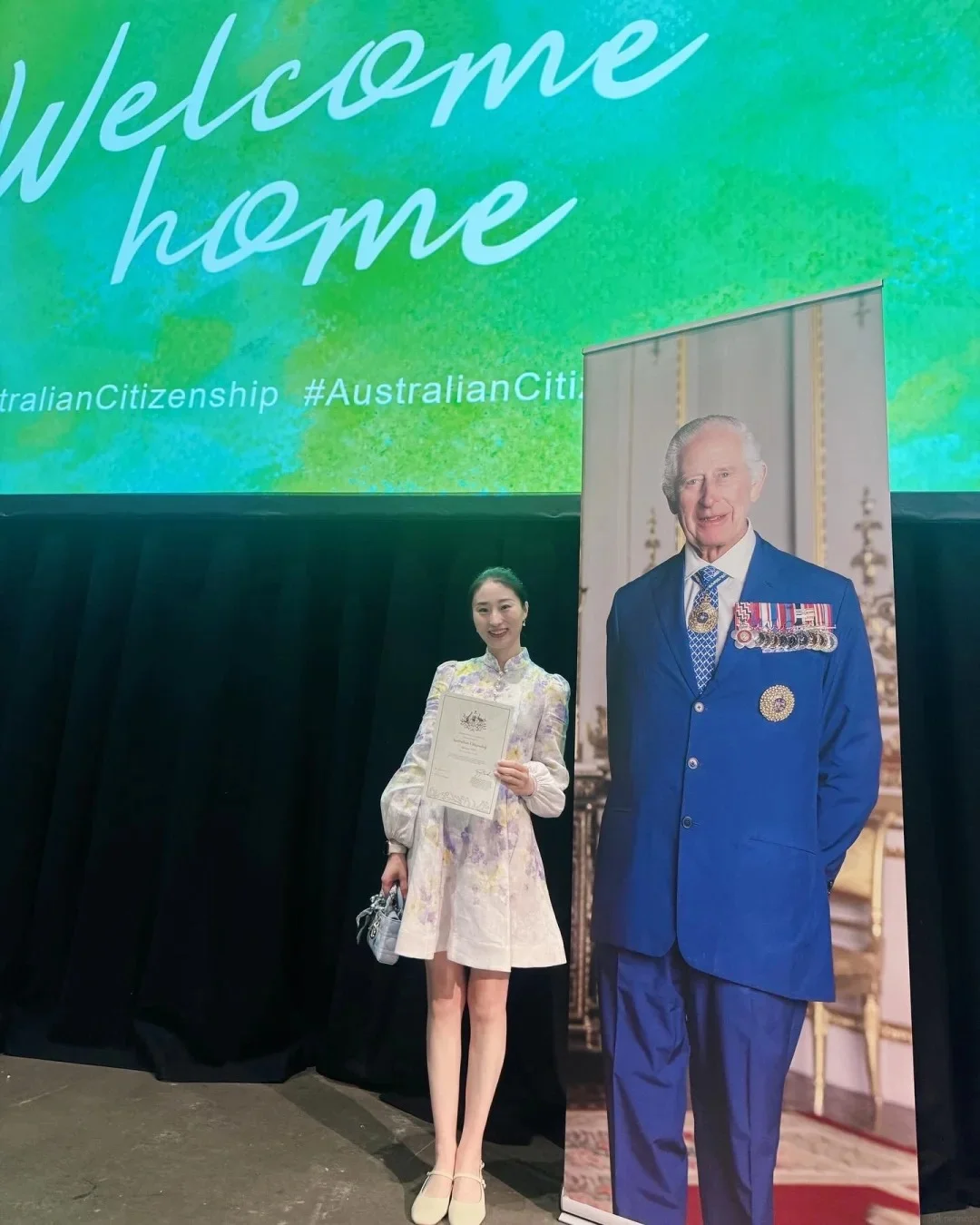 Woman at citizenship ceremony with Welcome Home screen